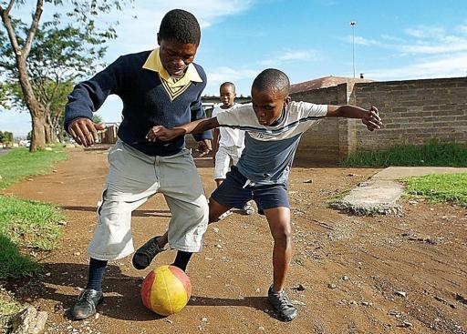   Ragazzini giocano a calcio nelle strade del ghetto di Soweto